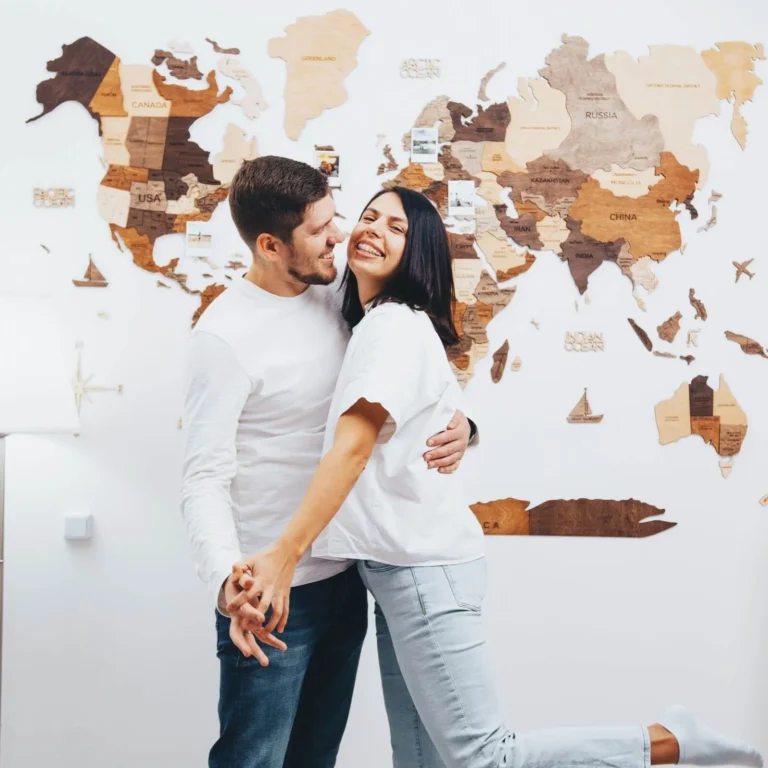 3D Wooden World Map Multicolor hanging on a living room wall behind a couple