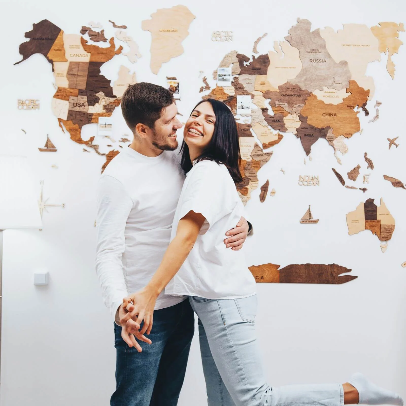 3D Wooden World Map Multicolor hanging on a living room wall behind a couple